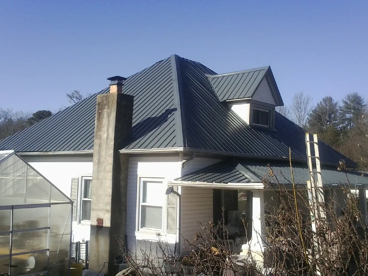 Dark blue standing seam metal roof on a white farmhouse with dormer — Slate & Tile Roof Repair by Roofing Brothers in Odell