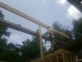 Carpenter setting a ridge beam over a new addition frame — Ice Dam Removal by Roofing Brothers in Odell