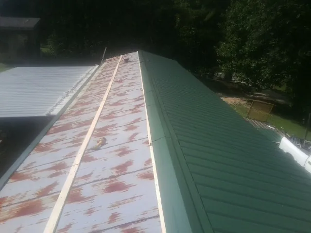 Old rusted panels beside newly installed green metal roofing — Wind Damage Roof Repair by Roofing Brothers in Odell