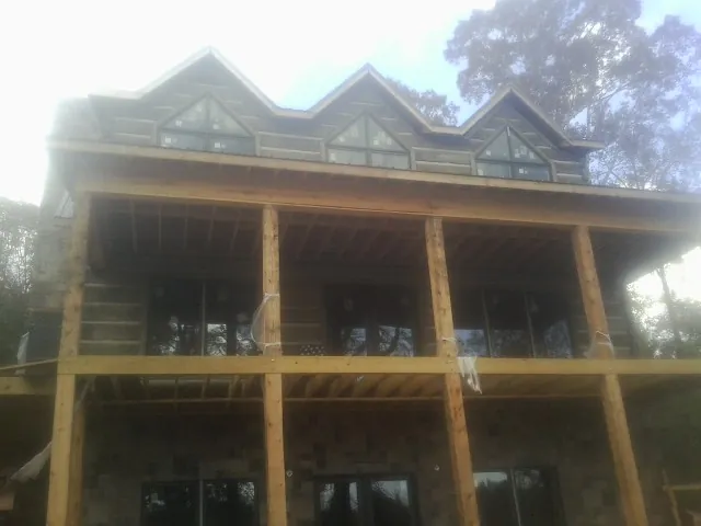 Dormers and porch framing on a large log home under construction — Roof Coating work by our crew in Odell