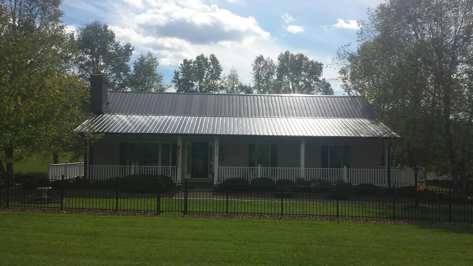 Gray metal roof on a brick ranch with a full width front porch — Gutter Guard Installation work by our crew in Odell
