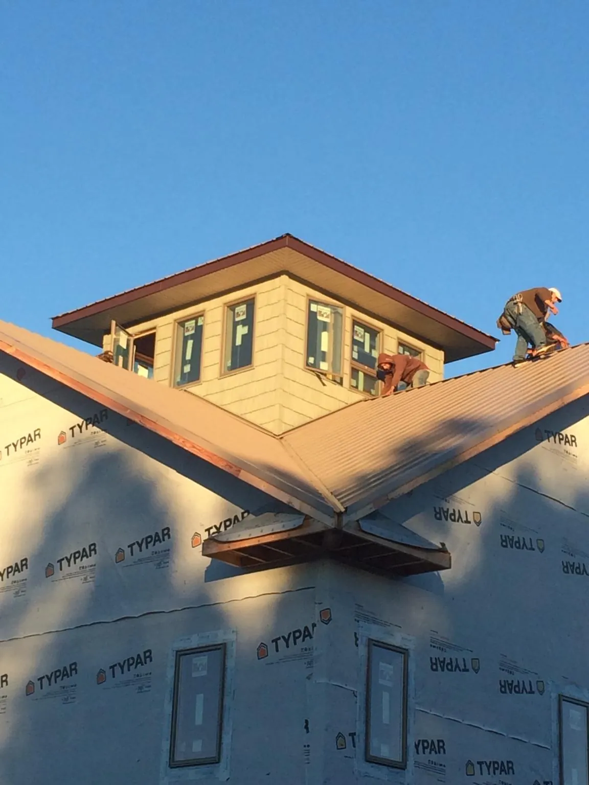 Roofers working around a rooftop cupola on a new metal roof at sunset — Roof Waterproofing in Odell by Roofing Brothers
